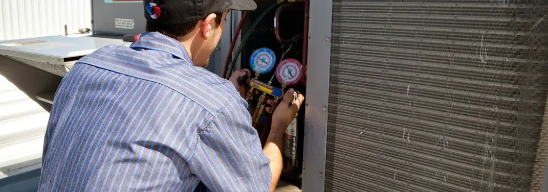 HVAC technician servicing a condenser unit in Dover